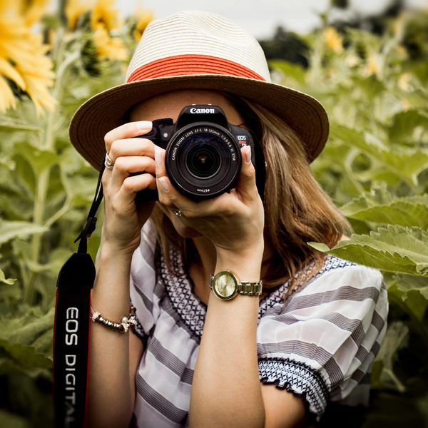 A passionate female photographer with her DSLR camera in hand focuses on framing the perfect shot.