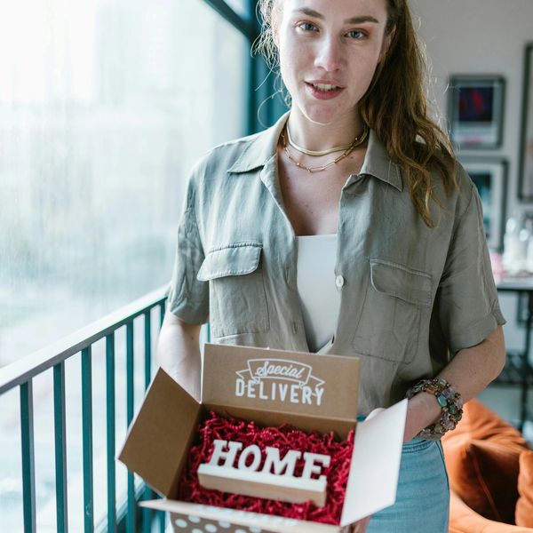 Woman holding a custom-designed box with 'HOME' sign, showing creative graphic design and branding