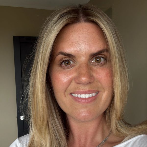 Smiling woman with blonde hair and white top.