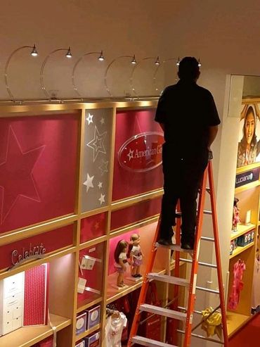 Rolando braving the ladder to clean the track lighting at the American Girl Store in San Francisco..