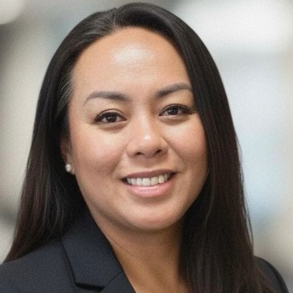 Smiling woman with long black hair wearing a black blazer.