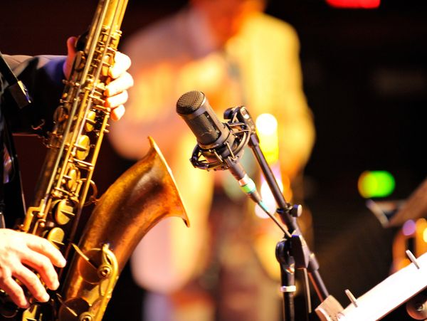 Close-up of saxophone and microphone on stage.