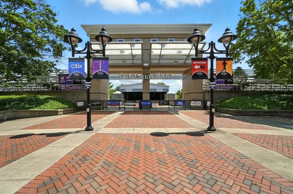 Entrance to an outdoor amphitheater with banners and lamp posts.