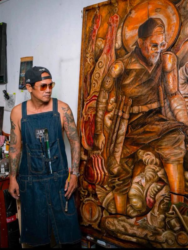 Artist standing next to his detailed wooden artwork.