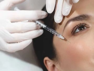 A woman receiving a cosmetic injection near her eye.