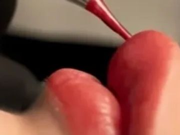 Close-up of lips being painted with red lipstick.