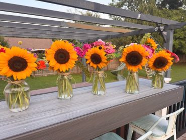 Sunflowers in glass jars on a wooden surface