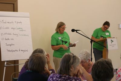 Mary Beth and Melissa wearing the green VIA shirts stand in front of leaders at statewide convention