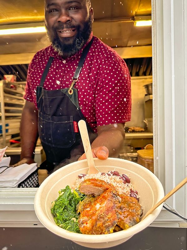 Warren serving up a rice bowl with jerk fried chicken, roasted garlic & kale, and rice and beans.