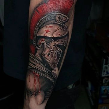 Tattoo of a Spartan warrior helmet with red accents and blood drops.