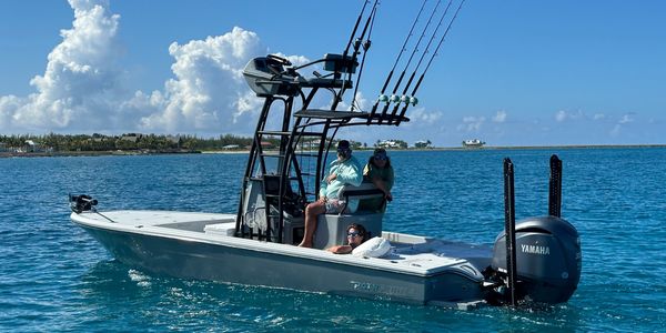 Three people on a fishing boat in clear blue waters under sunny skies.
