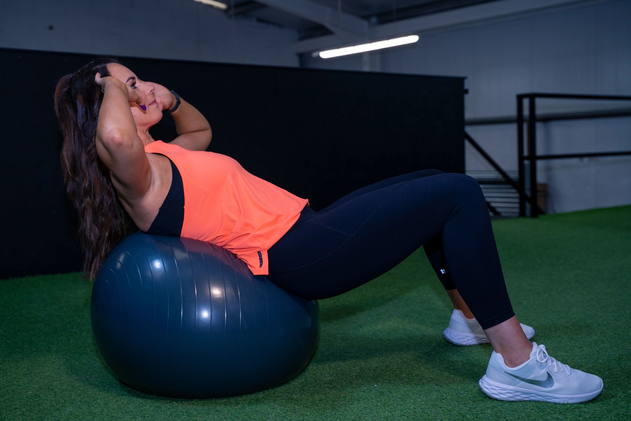 Woman doing crunches on an exercise ball indoors.