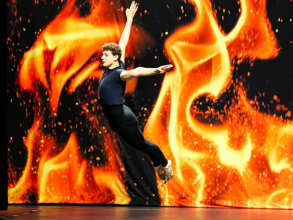 A dancer leaping in the air on the Ignite stage during their solo.