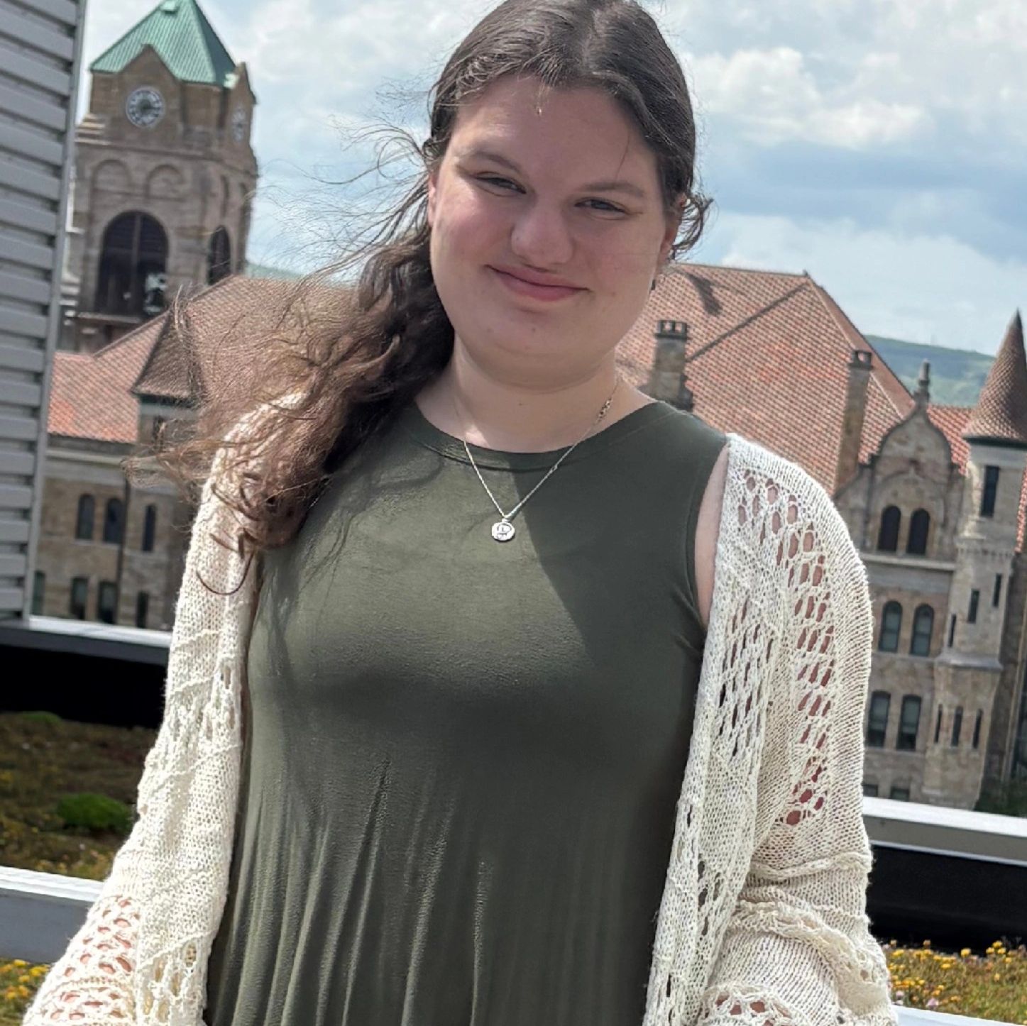 Young woman smiling outdoors with historic buildings in the background.