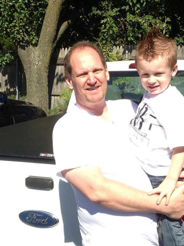 Man Holding a Young Boy in Front of a Truck