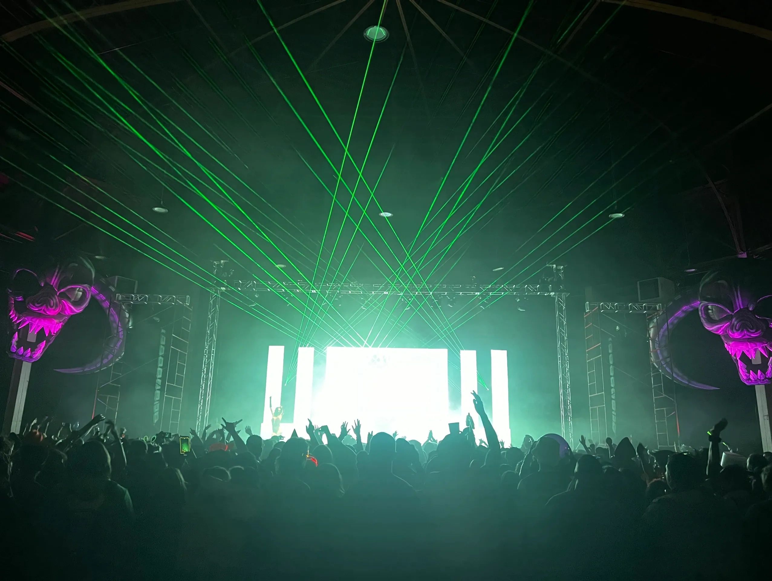 Green laser lights shine over a crowded concert stage.