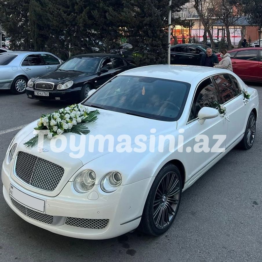 White luxury wedding car decorated with white flowers on the hood and doors.