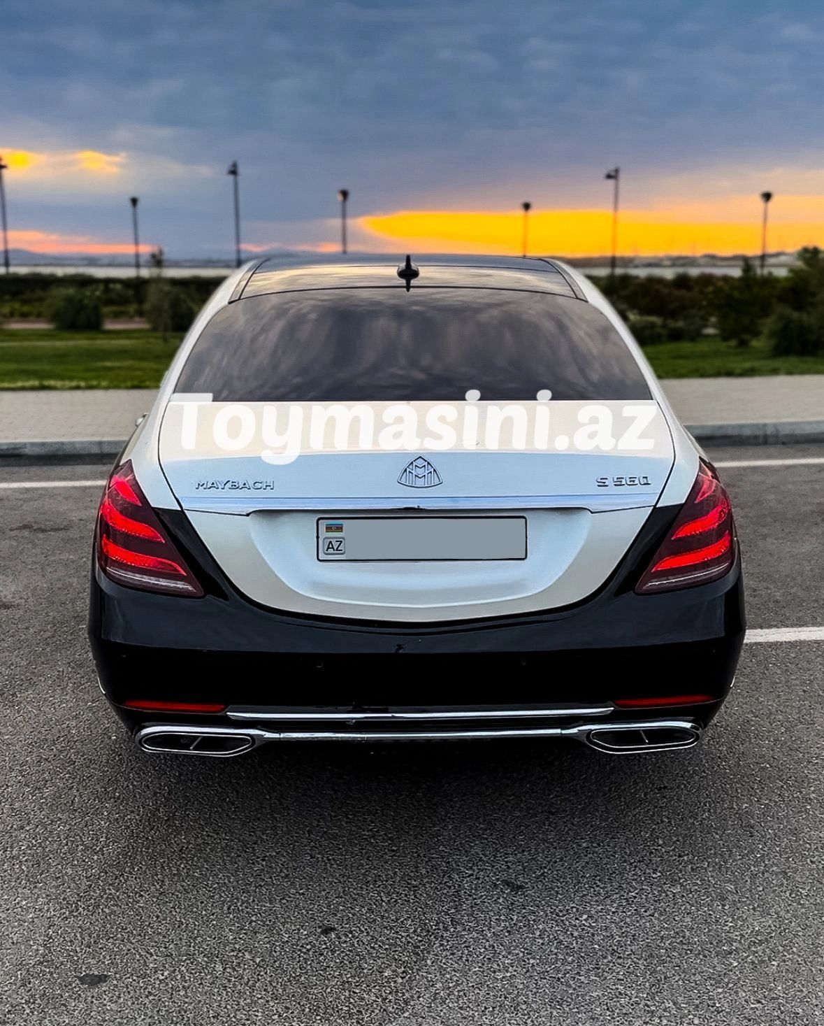 Rear view of a black and silver Maybach S560 luxury car at sunset.