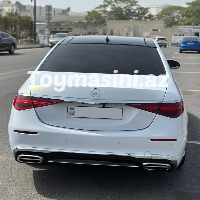 Rear view of a white Mercedes-Benz sedan parked on the street with tinted windows.