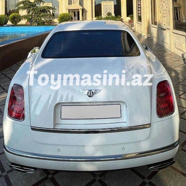 Rear view of a white Bentley car with tinted windows and luxury surroundings.