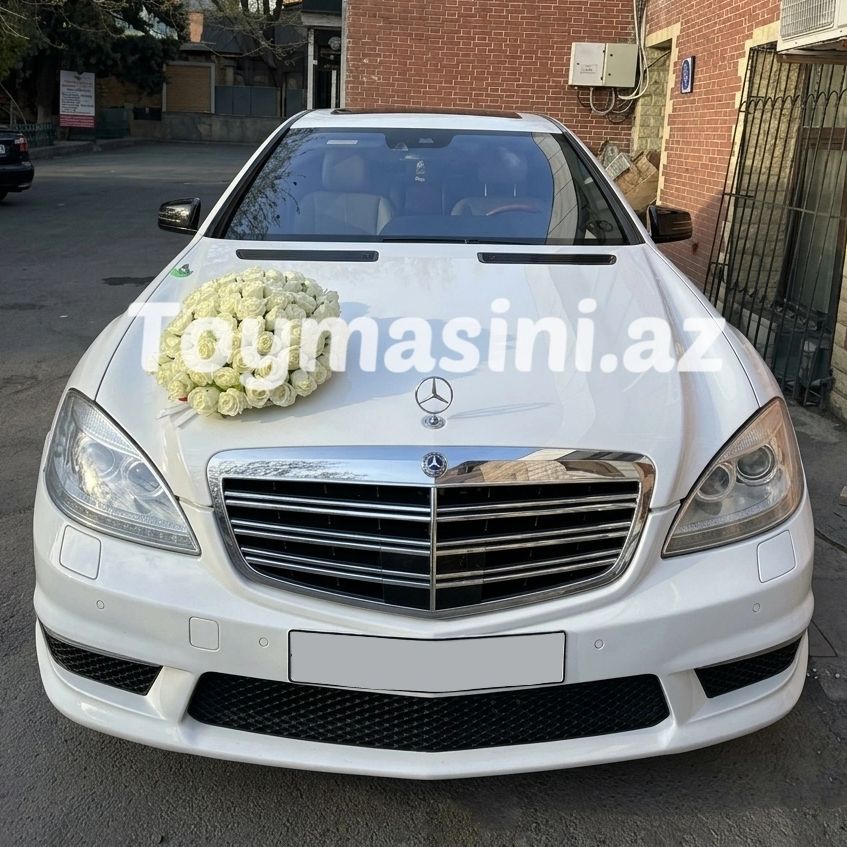 White Mercedes with a bouquet of white flowers on the hood.