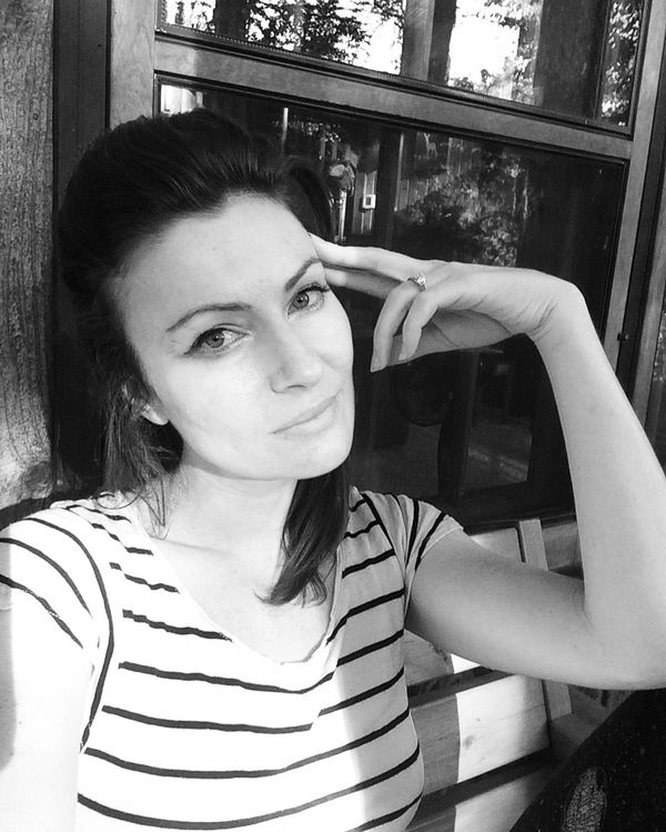 Woman posing with hand on head, wearing a striped shirt.