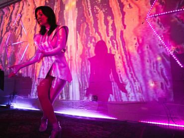 Woman dancing in colorful, vibrant lighting.