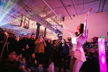 Performer in white engaging an audience indoors.
