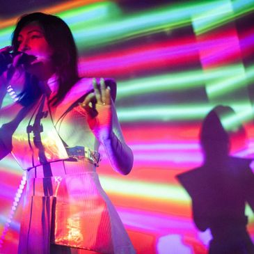 Singer performing with vibrant colorful light projections.