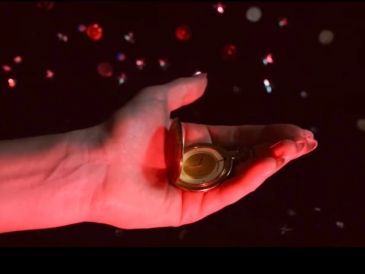 Hand holding an open pocket watch with red light.