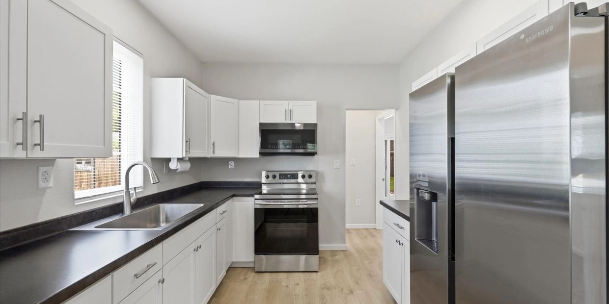 Modern kitchen with stainless steel appliances and white cabinets.