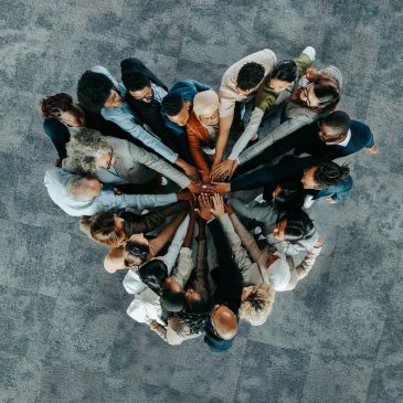 Diverse group uniting hands in a circle, symbolizing teamwork and solidarity.