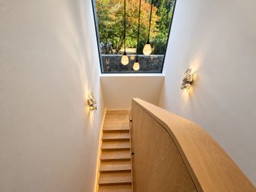 Modern staircase with wooden steps and pendant lights.