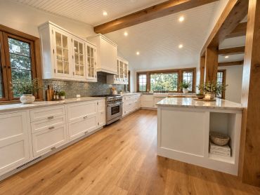 Bright modern kitchen with wooden floors and white cabinets.