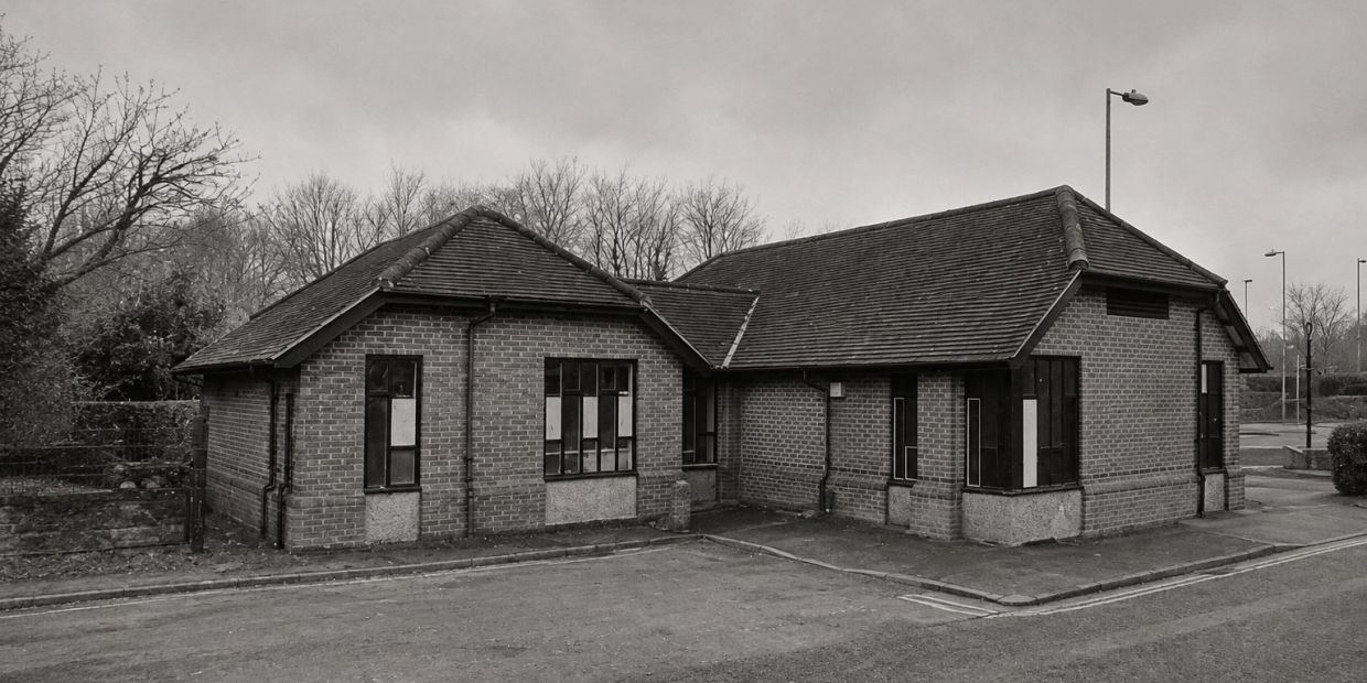 An old, empty brick building with a cloudy sky.