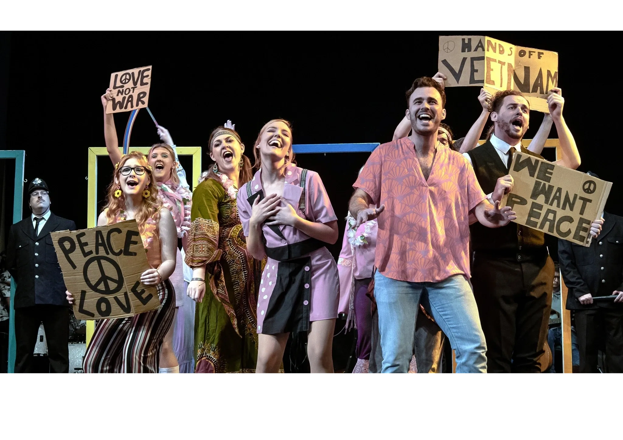 Group of actors performing as hippies on stage