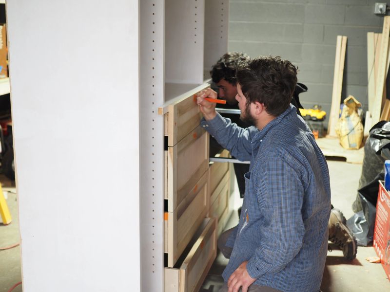 Two carpenters marking out drawers in the shop