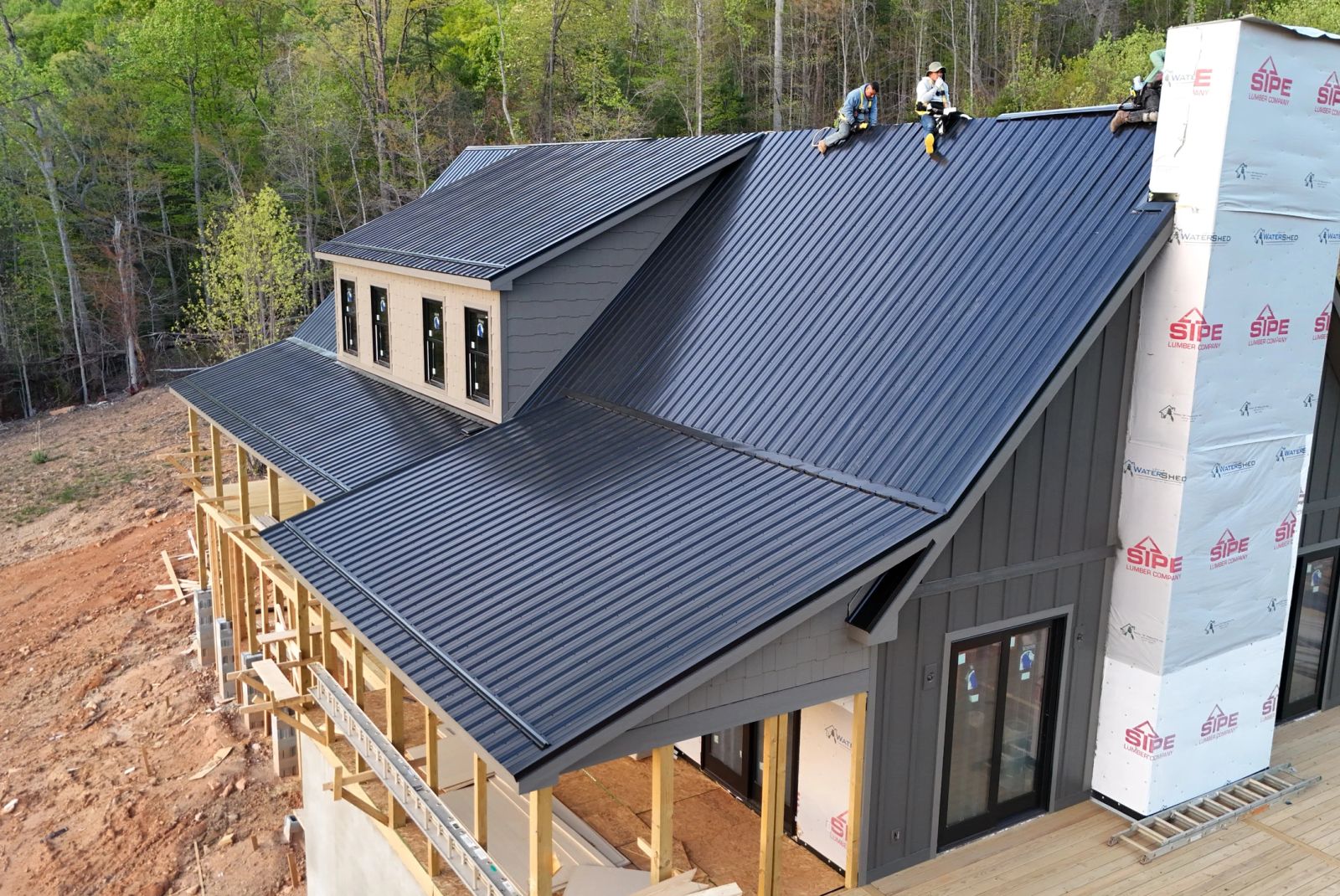 Standing seam roof panels being fixed at the ridge