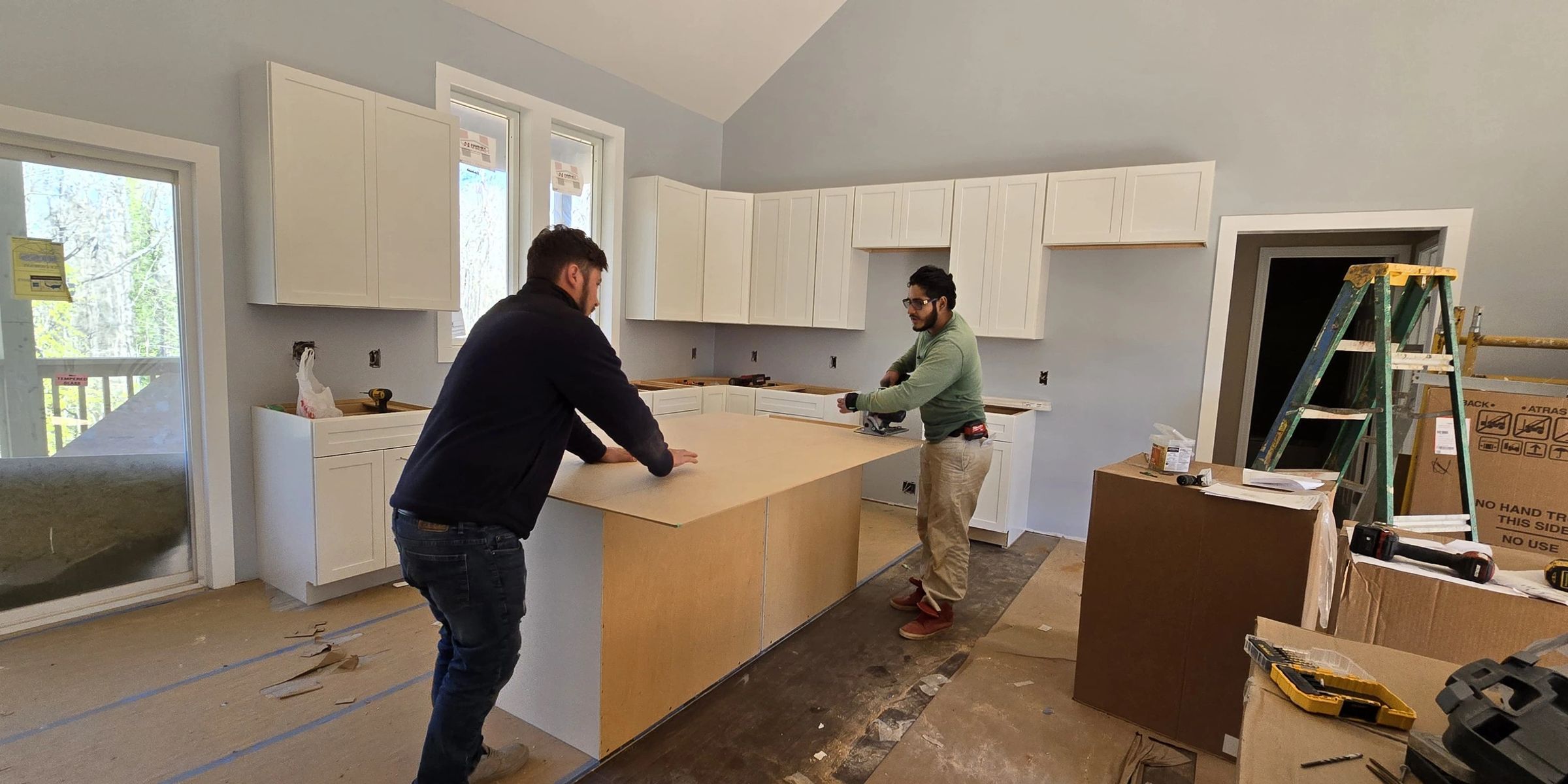 Two carpenters setting the kitchen island under a vaulted ceiling