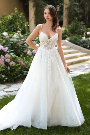 Bride in elegant white wedding dress with floral lace details.