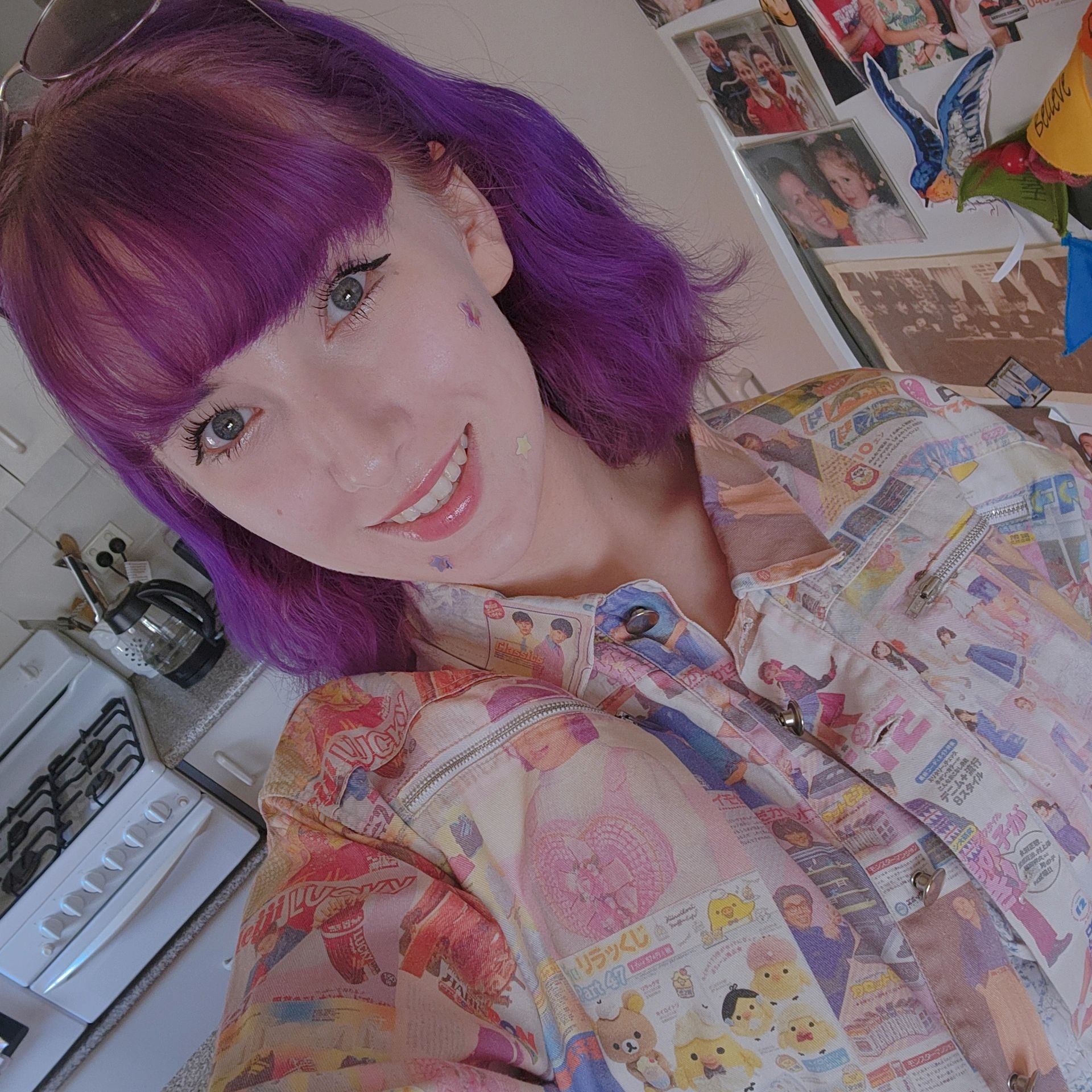 Young person with purple hair and star stickers on face smiling.