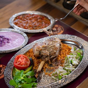 Kuzu tandır, bulgur pilavı ve sebzeler içeren geleneksel Türk yemeği.