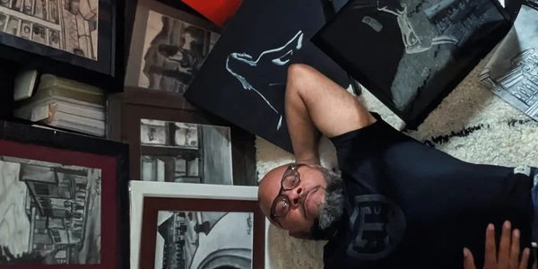 Man lying down surrounded by monochrome artwork and sketches.