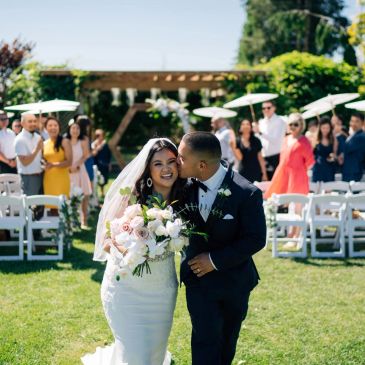 Newlywed couple sharing a kiss after their outdoor wedding ceremony.