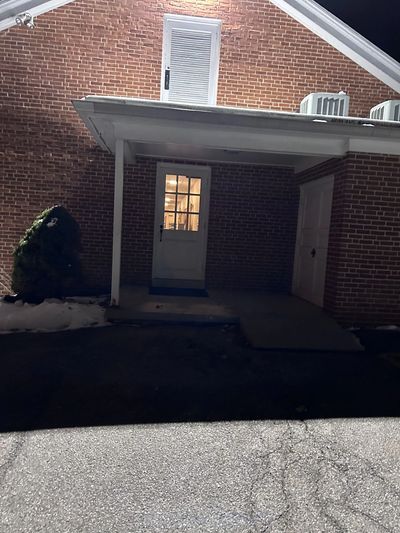 Lit doorway under a porch at night.
