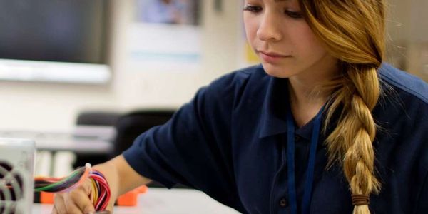 Young woman assembling or repairing a computer motherboard with cables.