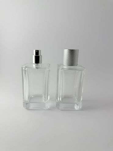 Dos frascos de perfume transparentes sobre fondo blanco.