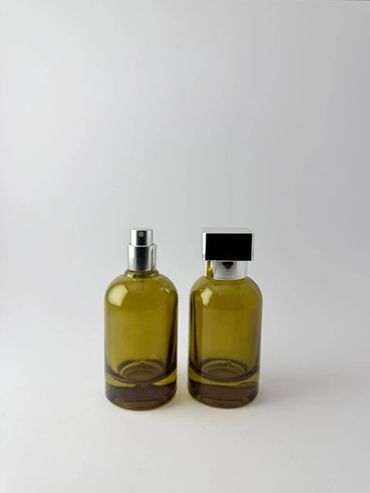 Dos frascos verdes de perfume sobre fondo blanco.