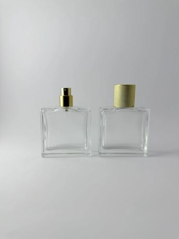 Dos frascos de perfume transparentes con tapas doradas.