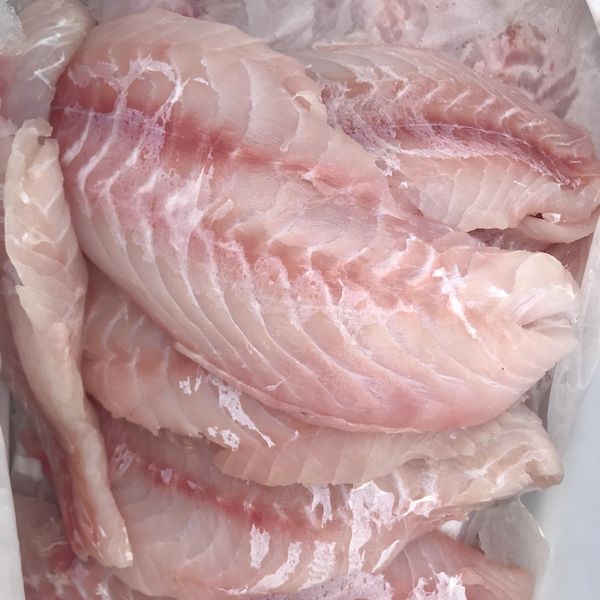 Fresh raw fish fillets stacked together, showing their pinkish-white flesh.